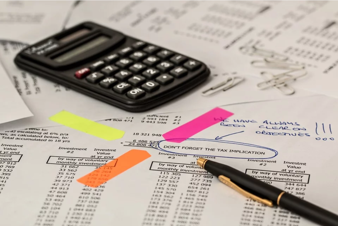 retenção de impostos: imagem mostra uma calculadora e uma caneta em cima de uma folha com contas