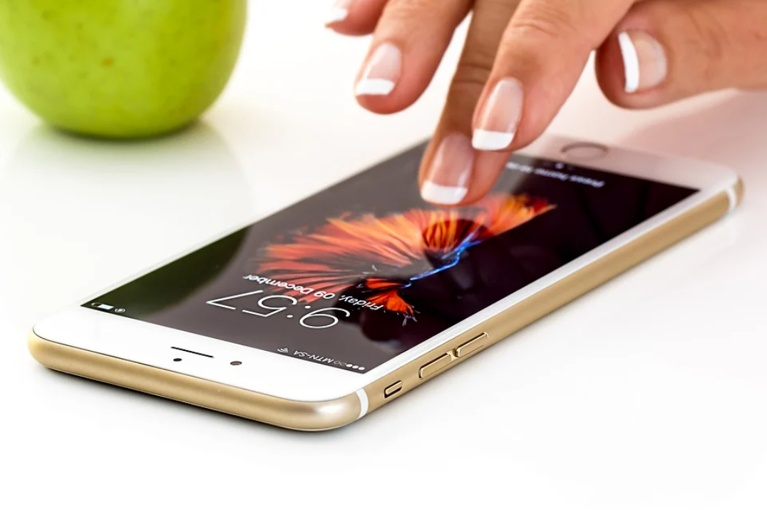 PIX: imagem de uma pessoa mexendo em smartphone que está sobre uma mesa. Ao lado do aparelho tem uma maçã verde.