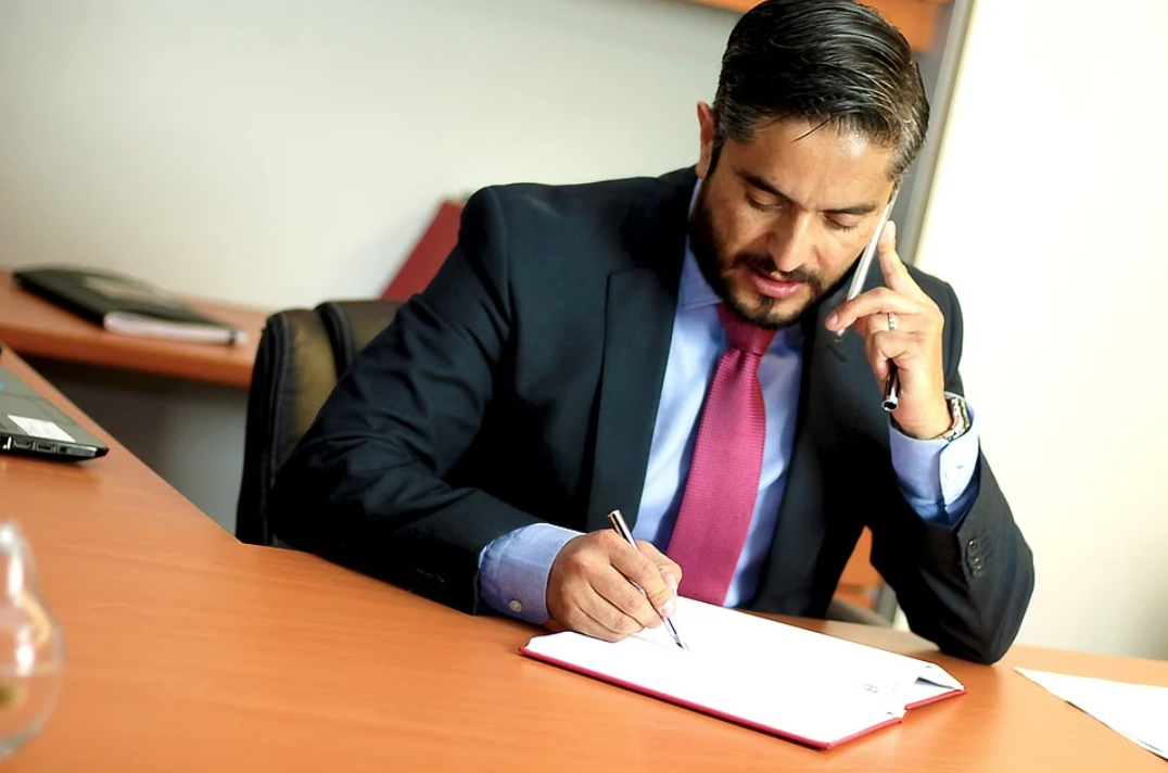 gestão de inadimplência: imagem mostra homem com terno e gravata ao telefone fazendo anotações