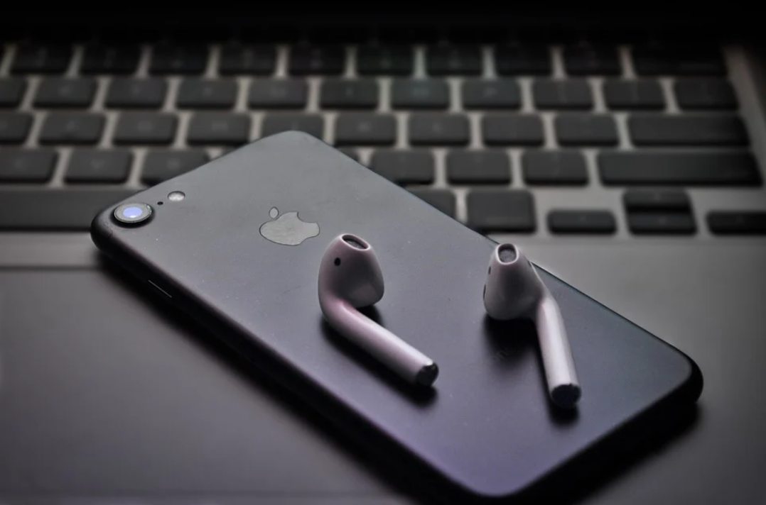 preço de obra: imagem mostra um smartphone da Apple com os fones sobre ele. Os aparelhos postos em cima do teclado de um notebook.